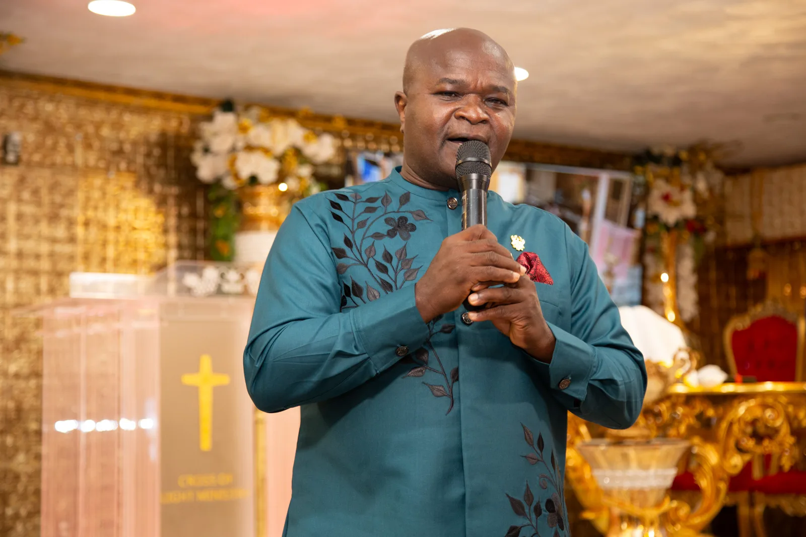 Pastor speaks at the mic — CLM cross pulpit clearly in the background