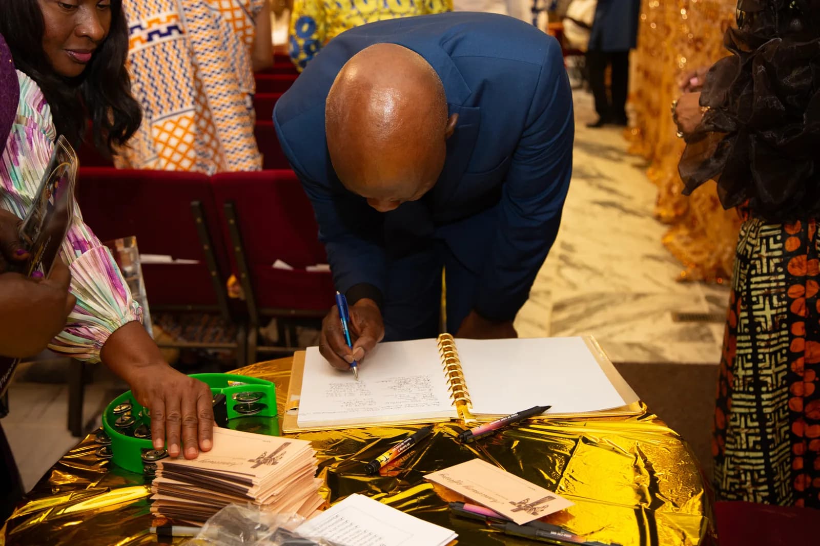 Guest leans over the anniversary guest-book table to sign