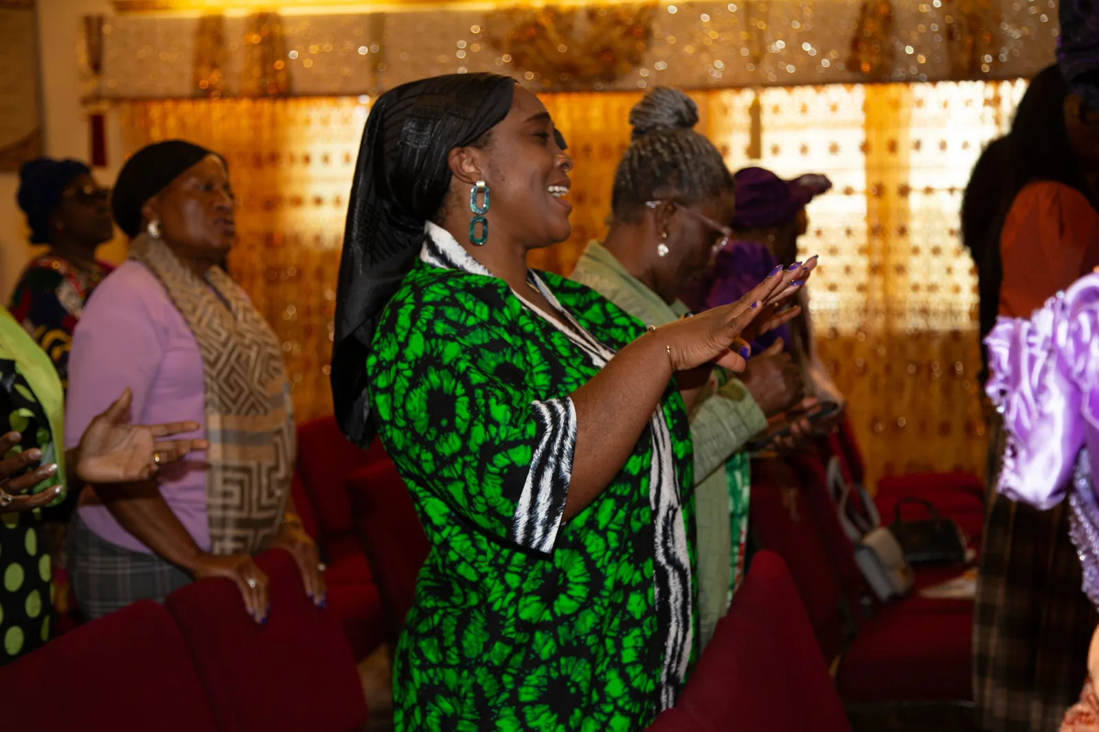 Woman in African print dress clapping with joy during praise